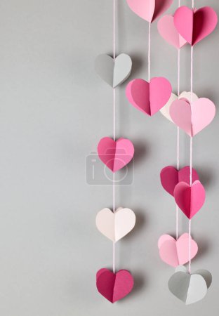 Foto de Coloridos corazones decorativos de papel que cuelgan sobre fondo gris, enfoque selectivo - Imagen libre de derechos