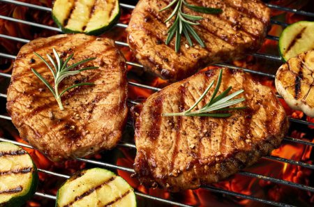 Téléchargez les photos : Steaks juteux fraîchement grillés et légumes sur le barbecue au charbon de bois brûlant - en image libre de droit