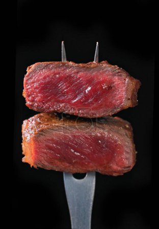 Photo for Two pieces of freshly grilled beef steak meat isolated on black background, selective focus - Royalty Free Image