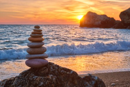 Concept of balance and harmony. Cairn stack of stones pebbles cairn on the beach coast of the sea in the nature on sunset. Meditative art of stone stacking