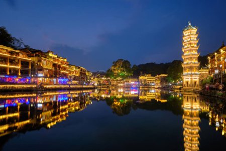 Photo for Chinese tourist attraction destination - Feng Huang Ancient Town (Phoenix Ancient Town) on Tuo Jiang River with Wanming Pagoda illuminated at night. Hunan Province, China - Royalty Free Image