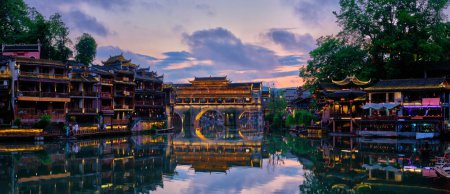 Photo for Chinese tourist attraction destination - panorama of Feng Huang Ancient Town (Phoenix Ancient Town) on Tuo Jiang River illuminated at night. Hunan Province, China - Royalty Free Image