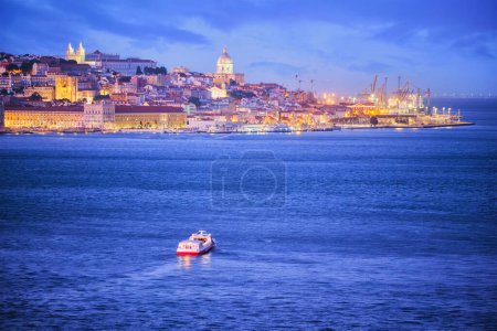 Foto de Vista nocturna de Lisboa sobre el río Tajo desde Almada con ferry y barco turístico al atardecer. Lisboa, Portugal - Imagen libre de derechos