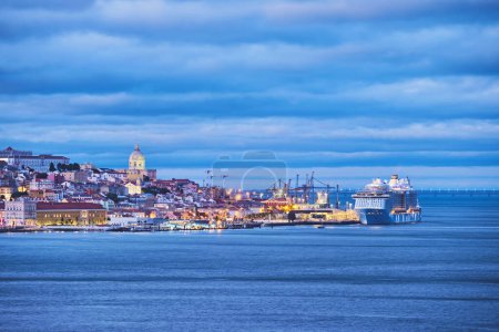 Foto de Vista de Lisboa sobre el río Tajo con ferry de paso desde Almada con crucero amarrado en el crepúsculo de la noche. Lisboa, Portugal - Imagen libre de derechos