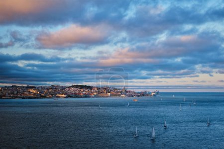 Photo for View of Lisbon over Tagus river from Almada with yachts tourist boats at sunset with dramatic sky. Lisbon, Portugal - Royalty Free Image