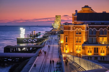 Foto de Lisboa, Portugal - 08 de agosto de 2022: Museo de la Electricidad en la Antigua Central Eléctrica de Tejo y Monumento a los Descubrimientos con paseo marítimo a orillas del río Tajo en Lisbom, Portugal iluminado por la noche - Imagen libre de derechos
