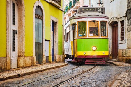Téléchargez les photos : Célèbre tramway jaune vintage 28 dans les rues étroites du quartier d'Alfama à Lisbonne, Portugal - symbole de Lisbonne, célèbre destination touristique populaire et attraction touristique - en image libre de droit