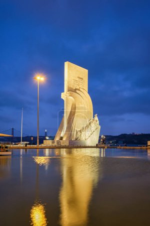 Foto de Lisboa, Portugal - 26 de agosto de 2022: Monumento a los Descubrimientos a orillas del río Tajo en el crepúsculo de la tarde con reflexión en la piscina de agua, Lisboa, Portugal, Europa - Imagen libre de derechos