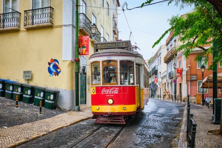 Foto de Lisboa, Portugal - 26 de agosto de 2022: famoso tranvía amarillo vintage en las estrechas calles del distrito de Alfama en Lisboa, Portugal - símbolo de Lisboa, famoso destino turístico y atracción turística - Imagen libre de derechos