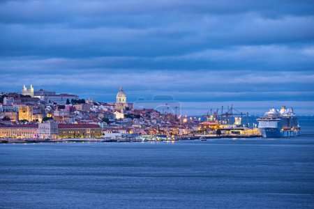 Photo for View of Lisbon over Tagus river with passing ferry boat from Almada with moored cruise liner in evening twilight. Lisbon, Portugal - Royalty Free Image