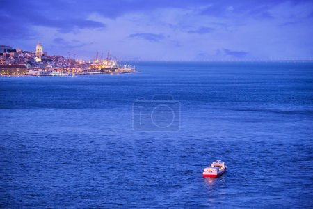 Téléchargez les photos : Vue nocturne de Lisbonne sur le Tage depuis Almada avec ferry et bateau touristique le soir au crépuscule. Lisbonne, Portugal - en image libre de droit