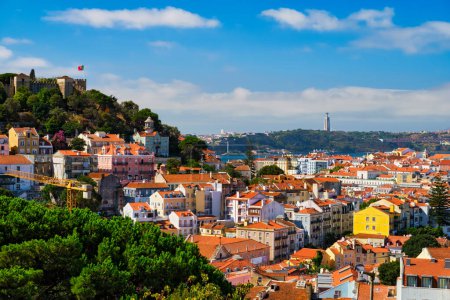 Photo for Lisbon famous view from Miradouro dos Barros tourist viewpoint over Alfama old city district with St. Georges Castle and Portugal flag, 25th of April Bridge, Christ the King statue. Lisbon, Portugal. - Royalty Free Image