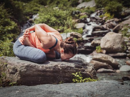 Photo for Vintage retro effect filtered hipster style image of Young sporty fit woman doing yoga - meditating in Baddha Padmasana (Bound Lotus Pose) outdoors at tropical waterfall - Royalty Free Image