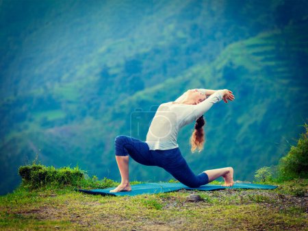 Téléchargez les photos : Yoga en plein air - femme en forme sportive pratique Hatha yoga asana Anjaneyasana - faible croissant pose posture en plein air dans les montagnes de l'Himalaya. Vintage effet rétro filtré image de style hipster
. - en image libre de droit