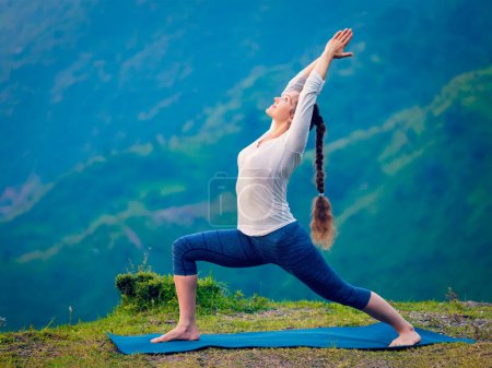 Photo for Yoga outdoors - sporty fit woman doing Ashtanga Vinyasa Yoga asana Virabhadrasana 1 Warrior pose posture in HImalayas mountains. Vintage retro effect filtered hipster style image. - Royalty Free Image