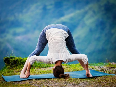 Téléchargez les photos : Exercice de yoga à l'extérieur - femme faisant Ashtanga Vinyasa Yoga asana Prasarita padottanasana D - large jambes courbées vers l'avant posent à l'extérieur. Vintage effet rétro filtré image de style hipster. - en image libre de droit