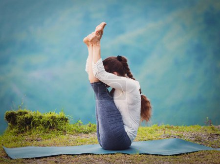 Foto de Yoga - mujer en forma deportiva practica Ashtanga Vinyasa yoga asana Urdhva mukha paschimottanasana - hacia arriba orientado intenso estiramiento oeste al aire libre. Vintage efecto retro filtrado hipster estilo imagen. - Imagen libre de derechos