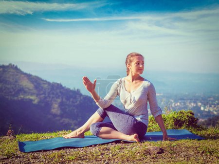 Téléchargez les photos : Exercice de yoga à l'extérieur femme faisant Ardha matsyendrasana asana demi-colonne vertébrale pose montagnes dans l'Himalaya en Inde le matin. Vintage effet rétro filtré image de style hipster. - en image libre de droit