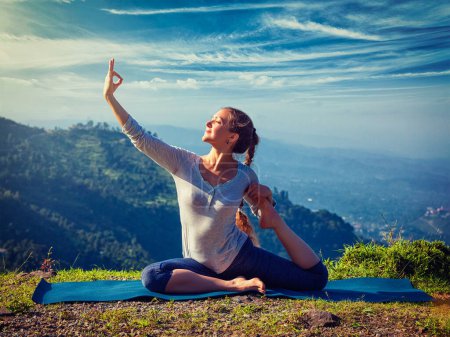 Téléchargez les photos : Yoga en plein air - jeune femme en forme sportive faisant du yoga d'étirement asana Eka pada rajakapotasana une pose de pigeon roi pattes dans les montagnes de l'Himalaya, en Inde. Vintage effet rétro filtré image de style hipster. - en image libre de droit