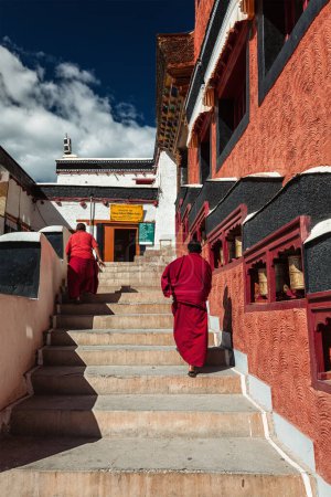 Photo for THIKSEY, INDIA - SEPTEMBER 13, 2012: Young Buddhist monks walking on stairs along prayer wheels in Thiksey gompa Tibetan Buddhist monastery, Ladakh, India - Royalty Free Image
