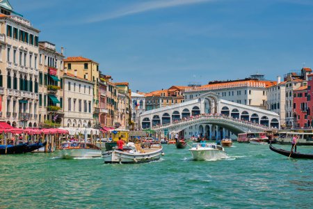 Foto de VENECIA, ITALIA - 19 DE JULIO DE 2019: Puente de Rialto con barcos y góndolas pasando por el Gran Canal, Venecia, Italia - Imagen libre de derechos