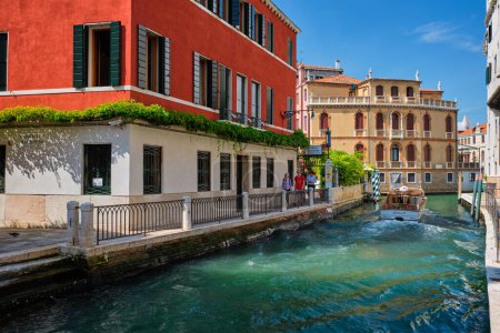 Photo for VENICE, ITALY - JULY 19, 2018: Narrow canal between colorful old houses with tourists in Venice, Italy - Royalty Free Image
