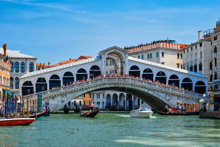 Foto de VENECIA, ITALIA - 19 DE JULIO DE 2019: Puente de Rialto con barcos y góndolas pasando por el Gran Canal, Venecia, Italia - Imagen libre de derechos