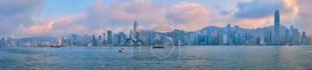 Téléchargez les photos : HONG KONG, CHINE - 28 AVRIL 2018 : Les gratte-ciel du centre-ville de Hong Kong surplombent le port de Victoria le soir, au coucher du soleil, avec des ferries pour bateaux touristiques. Hong Kong, Chine - en image libre de droit