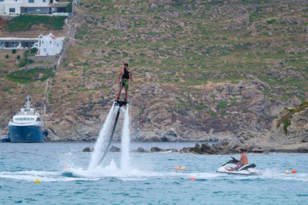 Photo for MYKONOS, GREECE - MAY 29, 2019: Man flying flyboarding on a Flyboard - hydroflighting device which supplies propulsion to drive the Flyboard invented by inventor Franky Zapata - Royalty Free Image