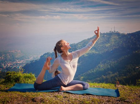 Téléchargez les photos : Yoga en plein air - jeune femme sportive en forme faisant du yoga asana Eka pada rajakapotasana pose de pigeon roi à une jambe dans les montagnes de l'Himalaya, en Inde. Vintage effet rétro filtré image hipster - en image libre de droit