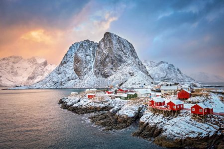 Téléchargez les photos : Célèbre attraction touristique Hamnoy village de pêcheurs sur les îles Lofoten, Norvège avec des maisons de rorbu rouge. Avec chute de neige en hiver au lever du soleil - en image libre de droit
