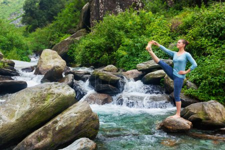 Photo for Yoga outdoors - woman doing Ashtanga Vinyasa Yoga balance asana Utthita Hasta Padangushthasana - Extended Hand-To-Big-Toe Pose position posture outdoors at waterfall - Royalty Free Image