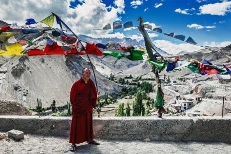 Photo for LAMAYURU, INDIA - SEPTEMBER 10, 2011: Buddhist monk standing outside with lugta prayer flags in Lamayuru gompa Buddhist monastery in Ladakh, India - Royalty Free Image