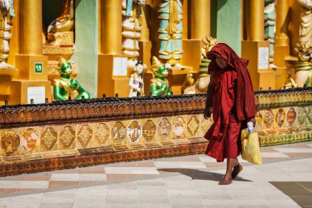 Téléchargez les photos : YANGON, MYANMAR - 3 JANVIER 2014 : Vieux moine bouddhiste marchant dans la pagode Shwedagon Paya - la pagode bouddhiste la plus sacrée du Myanmar - en image libre de droit