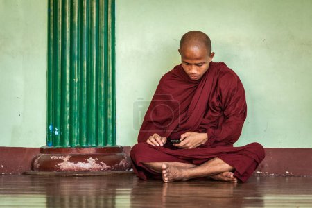 Foto de YANGON, MYANMAR - 3 DE ENERO DE 2014: Monje budista con teléfono en la pagoda Shwedagon Paya. Yangón, Myanmar - Imagen libre de derechos