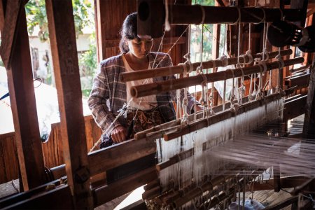 Téléchargez les photos : INLE LAKE, MYANMAR - 8 JANVIER 2014 : Une femme birmane tisse du tissu dans une usine de tissage où le textile est fabriqué de manière traditionnelle - en image libre de droit