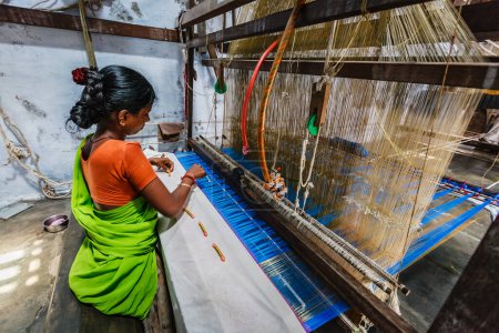 Photo for KANCHIPURAM, INDIA - SEPTEMBER 12, 2009: Woman weaving silk sari on loom. Kanchipuram is famous for hand woven silk sarees and most of the city's workforce is involved in weaving industry - Royalty Free Image