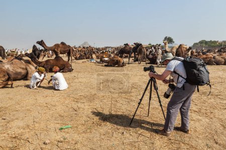 Foto de PUSHKAR, INDIA - 21 DE NOVIEMBRE DE 2012: Fotógrafo tomando fotos en la feria de camellos Pushkar Pushkar Mela - feria anual de camellos y ganado, una de las ferias de camellos y atracciones turísticas más grandes del mundo - Imagen libre de derechos