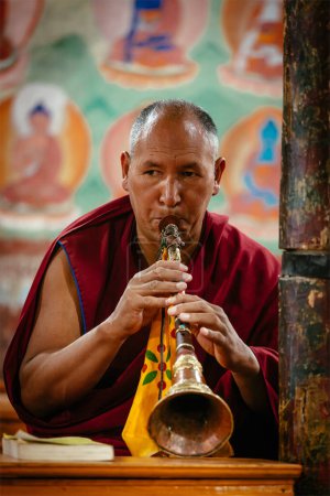 Photo for THIKSEY, INDIA - SEPTEMBER 4, 2011: Tibetan Buddhist monk plays religios music intstrument during prayer in Thiksey gompa Buddhist monastery of Yellow Hat Gelugpa sect largest gompa in central Ladakh - Royalty Free Image