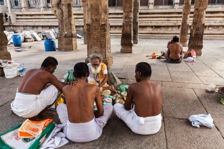 Téléchargez les photos : MADURAI, INDE - 16 FÉVRIER 2013 : prêtre brahmane indien (société traditionnelle hindoue) et pèlerins dans le célèbre temple Meenakshi Amman - temple hindou historique situé dans la ville du temple Madurai - en image libre de droit