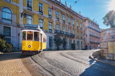 Photo for Famous vintage yellow tram 28 in the narrow streets of Alfama district in Lisbon, Portugal - symbol of Lisbon, famous popular travel destination and tourist attraction - Royalty Free Image