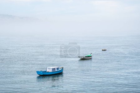 Photo for Boats in river on misty morning with background with heavy fog. Lisbon, Portugal - Royalty Free Image