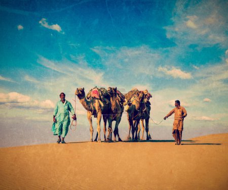 Foto de Imagen de viaje de estilo hipster retro vintage del fondo de viaje de Rajastán: dos camellos indios (conductores de camellos) con camellos en las dunas del desierto de Thar. Jaisalmer, Rajastán, India - Imagen libre de derechos