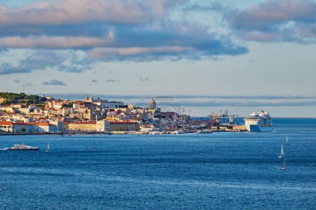 Foto de Vista de Lisboa sobre el río Tajo desde Almada con yates barcos turísticos y ferry de pasajeros y crucero amarrado en el atardecer con cielo dramático. Lisboa, Portugal - Imagen libre de derechos