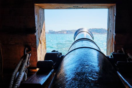 Photo for Sea view out of a gunport in hull of the ship over the gun cannon muzzle in on the gun deck of a sailing ship of Age of Sail - Royalty Free Image