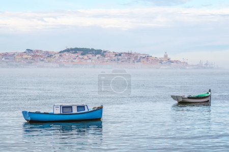 Foto de Barcos de pesca en el río Tajo en la mañana brumosa con Lisboa en el fondo con niebla. Lisboa, Portugal - Imagen libre de derechos