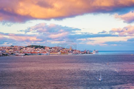 Téléchargez les photos : Vue de Lisbonne sur le Tage depuis Almada avec des yachts bateaux de tourisme et paquebot de croisière amarré au coucher du soleil avec un ciel spectaculaire. Lisbonne, Portugal - en image libre de droit