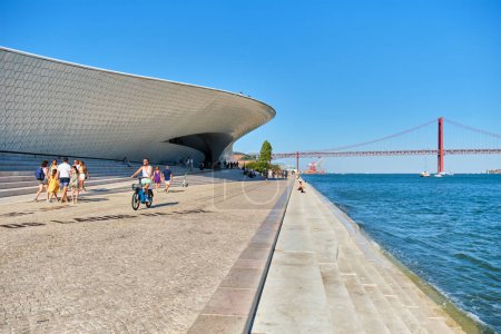Photo for Lisbon, Portugal - August 08, 2022: MAAT - Museum of Art, Architecture and Technology is a modern building on a bank of Tagus river with 25th of April bridge in background. Lisbon, Portugal - Royalty Free Image