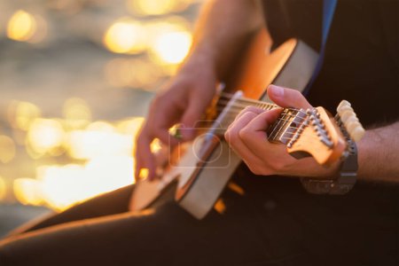 Téléchargez les photos : Musicien de rue jouant des mains de guitare électrique avec prise de guitare gros plan avec de l'eau en arrière-plan - en image libre de droit