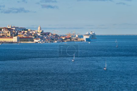 Foto de Vista de Lisboa sobre el río Tajo desde Almada con yates, barcos turísticos y cruceros amarrados al atardecer. Lisboa, Portugal - Imagen libre de derechos